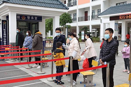 粤桂小学教师在给学生扫码测温。