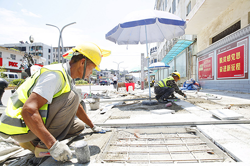 蝶城路施工现场，工作人员铺地砖。（卢昱霞　摄）