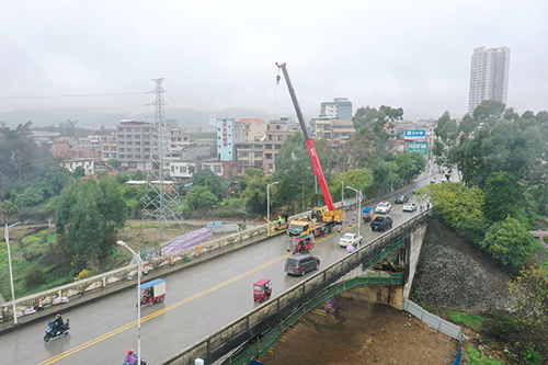 吊车在将施工所需的脚手架等器材吊至桥面。（陈建倬　摄）