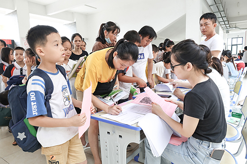 学生在家长陪同下办理入学手续。（陈素珍　摄）