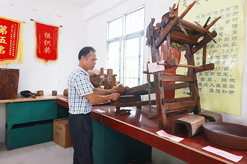 潘世模为村史室的老物件拂去灰尘。